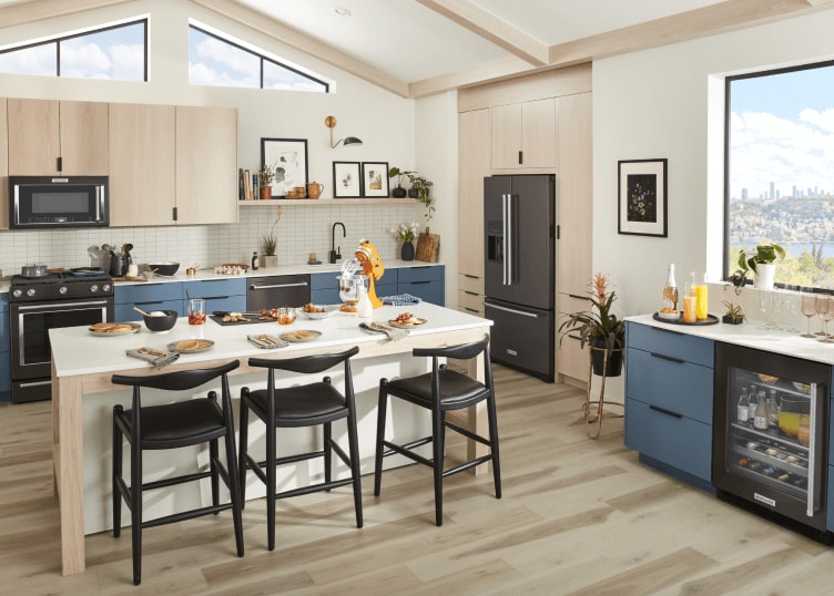 A contemporary kitchen with sleek blue cabinetry, black stainless steel appliances and a bright, honey colored KitchenAid® stand mixer.