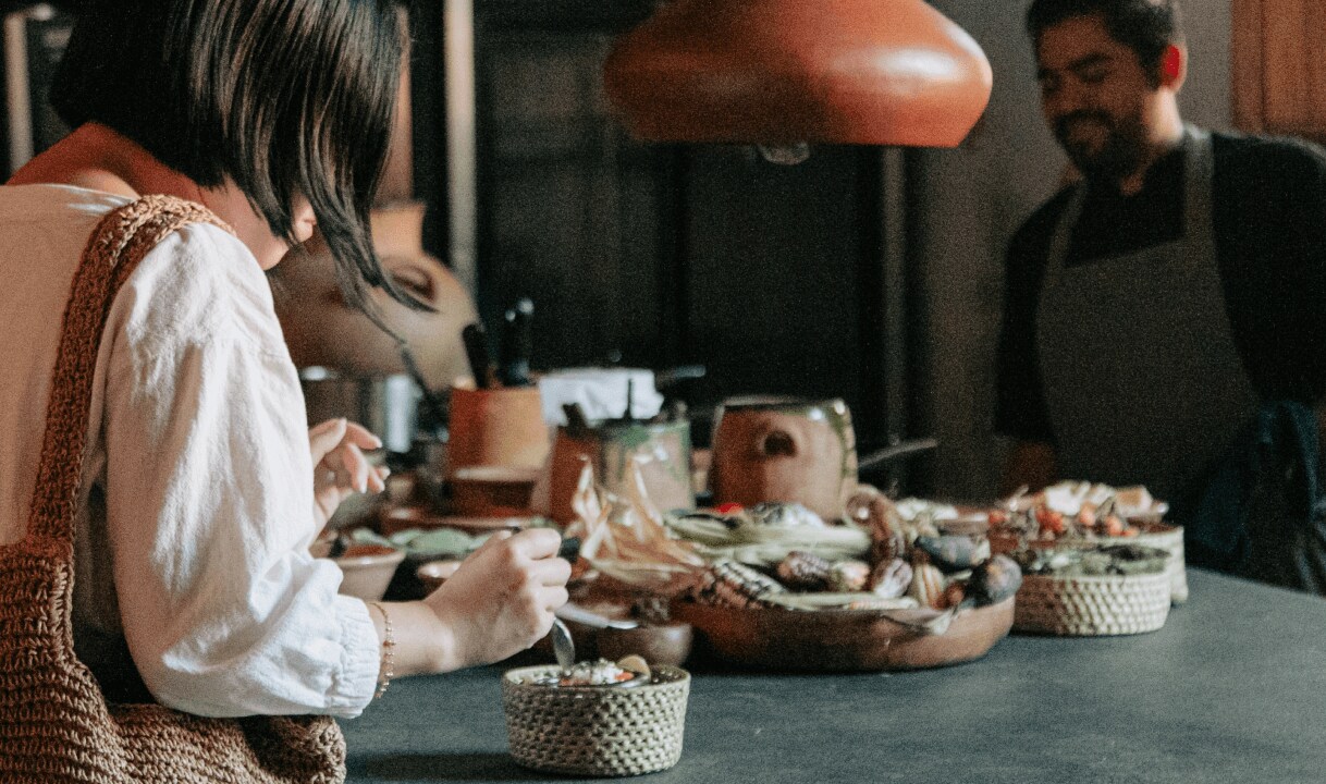 Ethaney Lee tasting Oaxacan dishes in a restaurant.