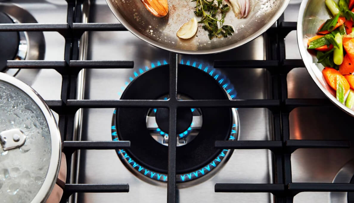 A variety of pans arranged around a lit gas burner.