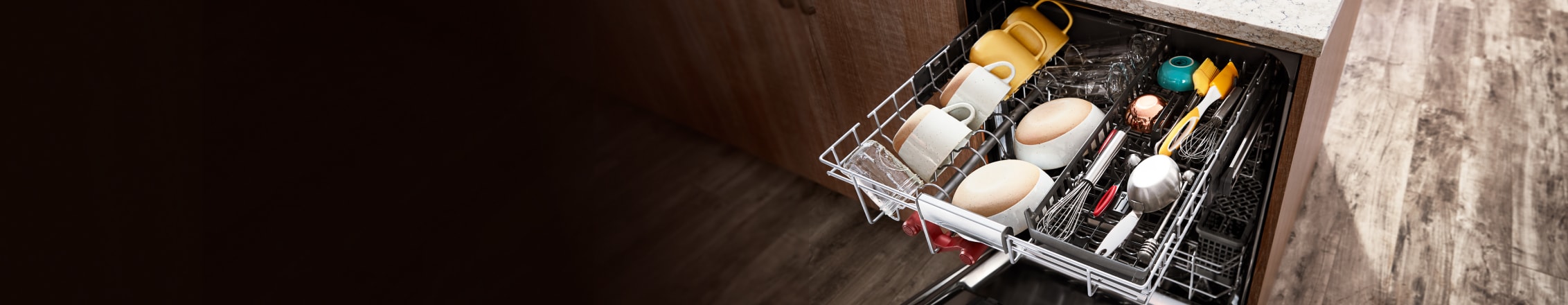 A top-down view of the fully loaded top rack in the KitchenAid 3rd Level Rack Dishwasher — with bowls, mugs and large cooking utensils laying in neatly organized rows.