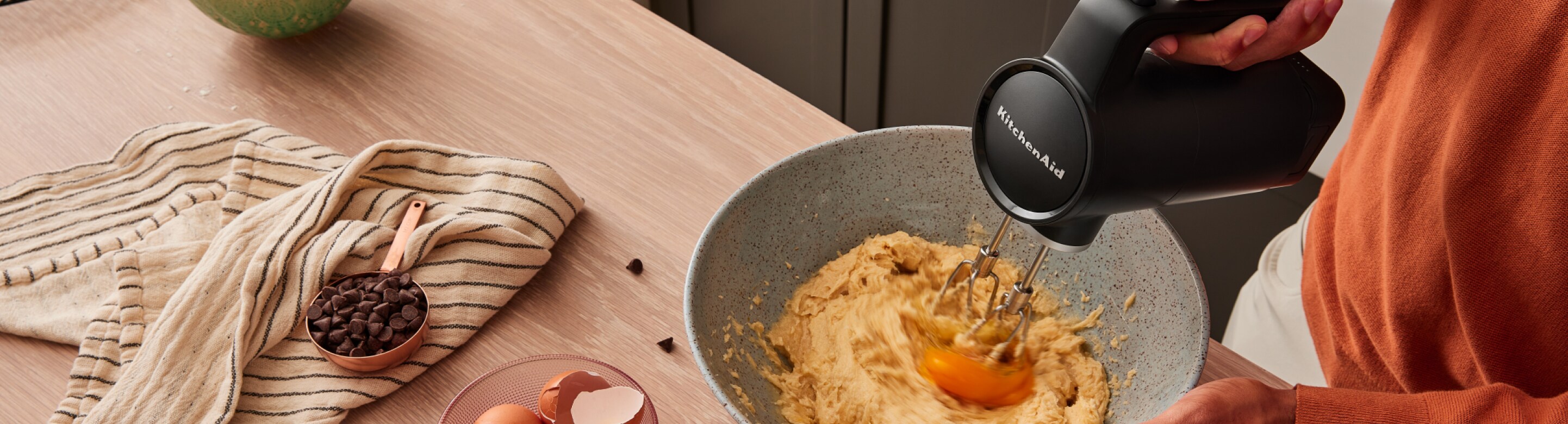 A person using the KitchenAid Go™ Cordless Hand Mixer to mix cookie dough.