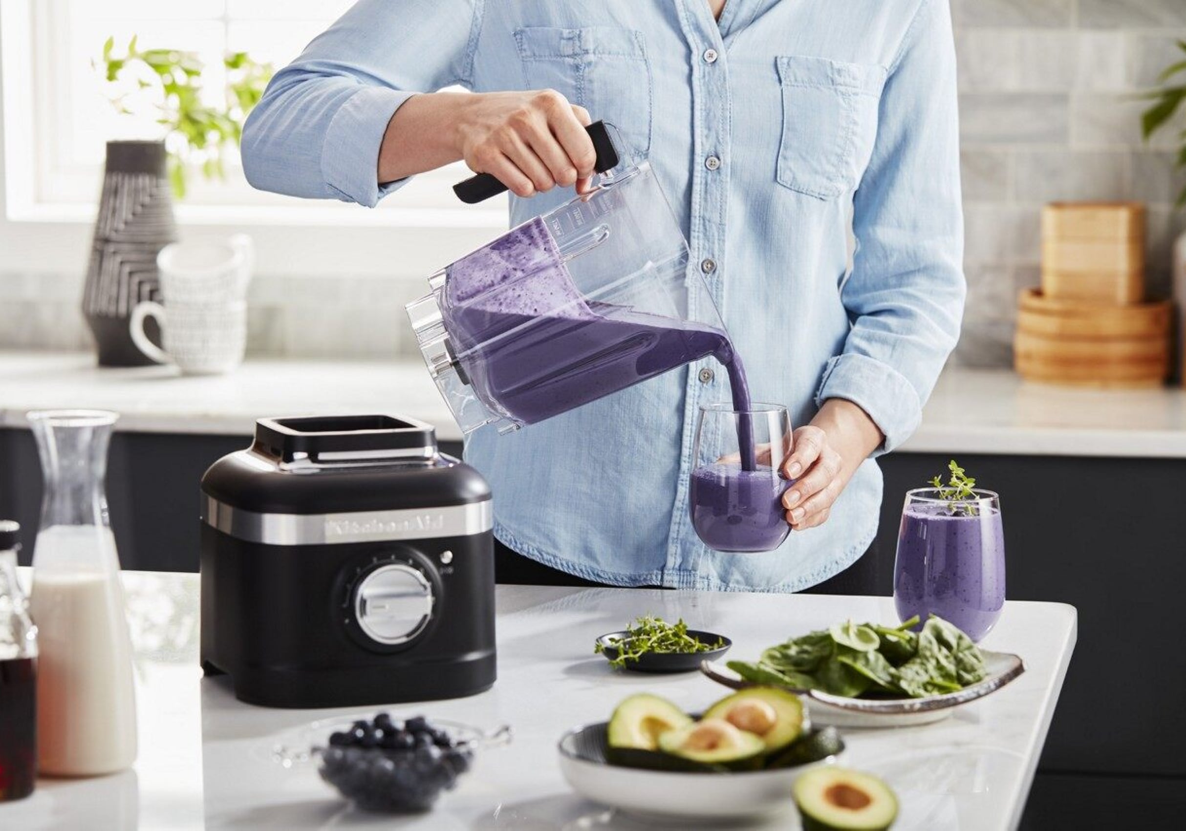 A person pouring a purple smoothie from a KitchenAid® blender. A person pouring a purple smoothie from a KitchenAid® blender.