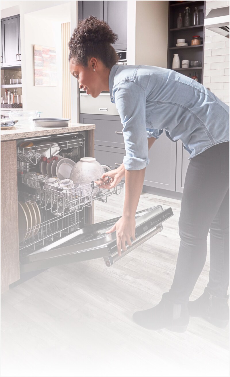Woman closing a dishwasher 
