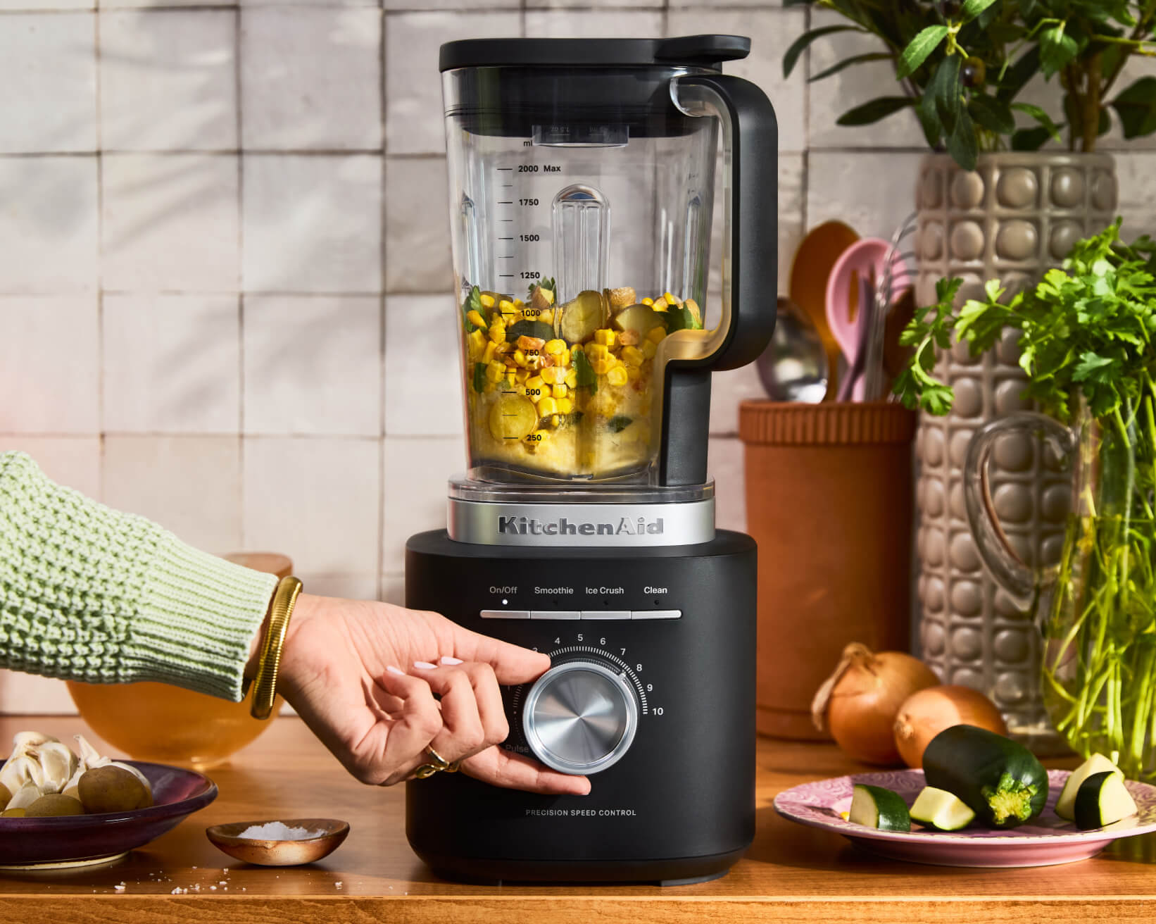 A matte black KitchenAid® blender with chunky yellow salsa inside