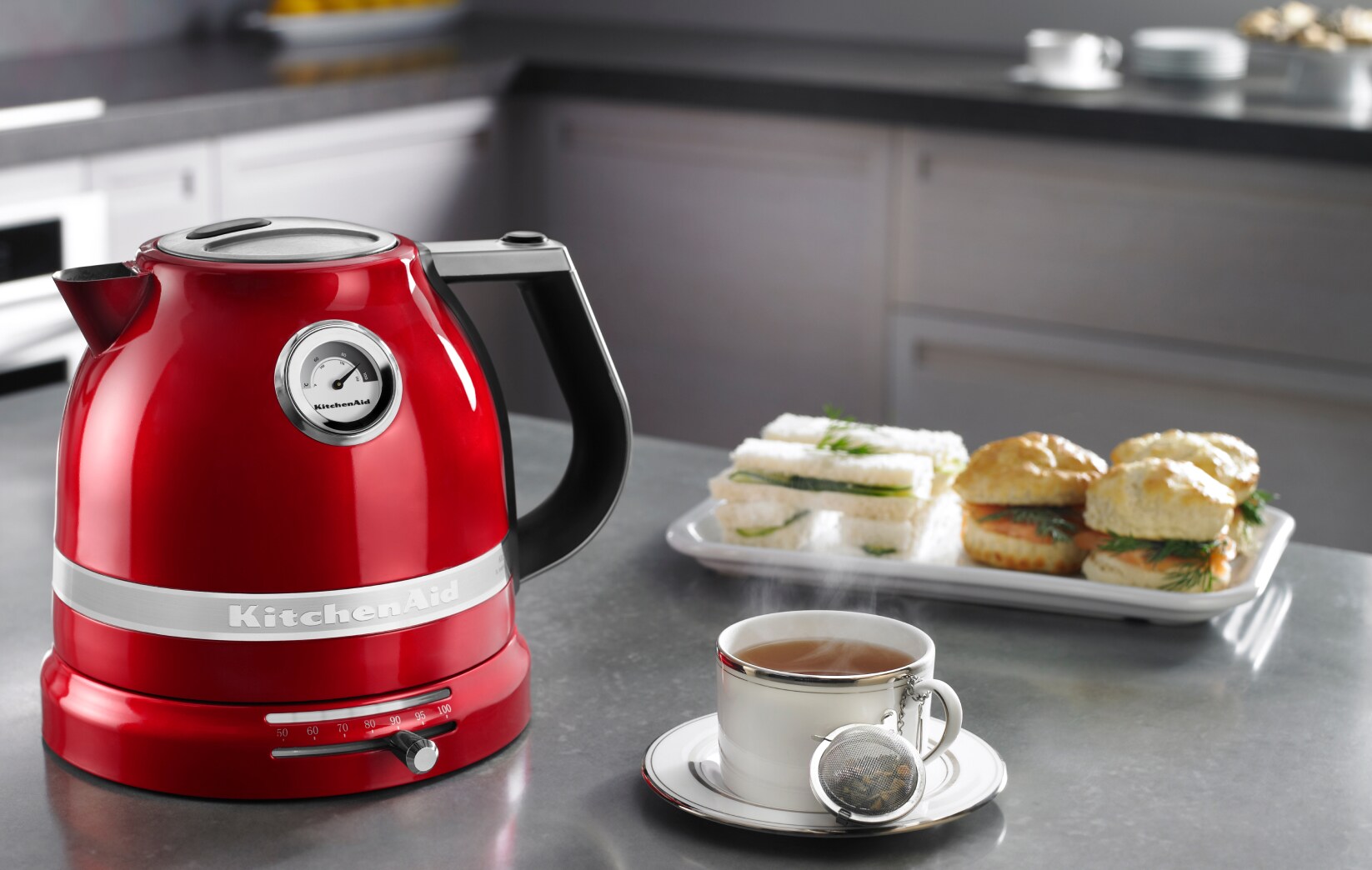 A KitchenAid® Pro Line® Series Electric Kettle on a countertop with tea and baked goods.