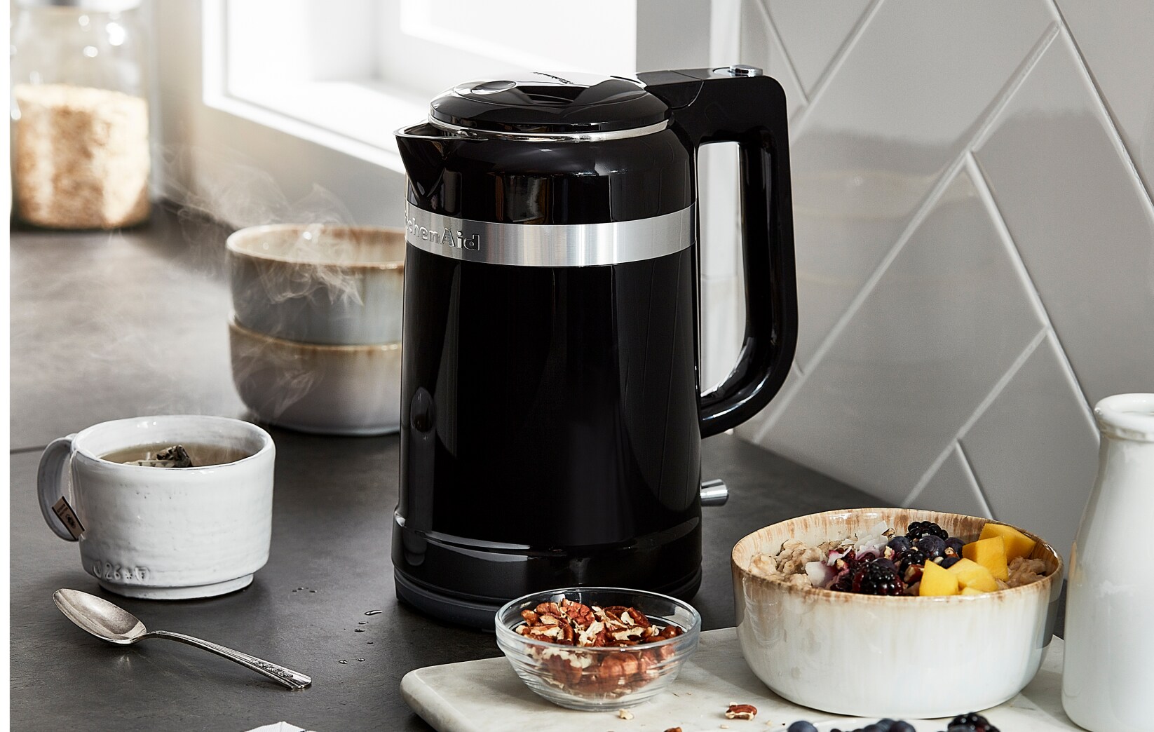 A KitchenAid® Electric Kettle next to a bowl of fruit.
