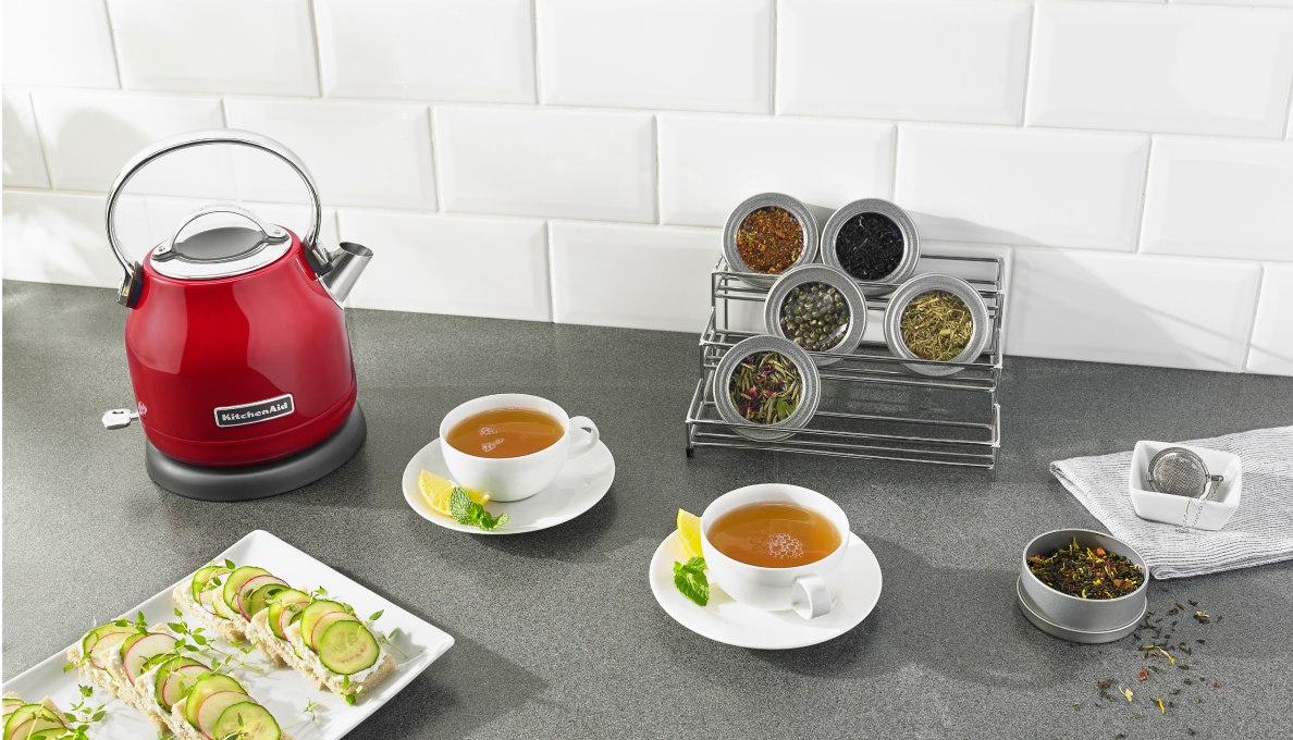 A KitchenAid® Kettle next to cups of tea and snacks.