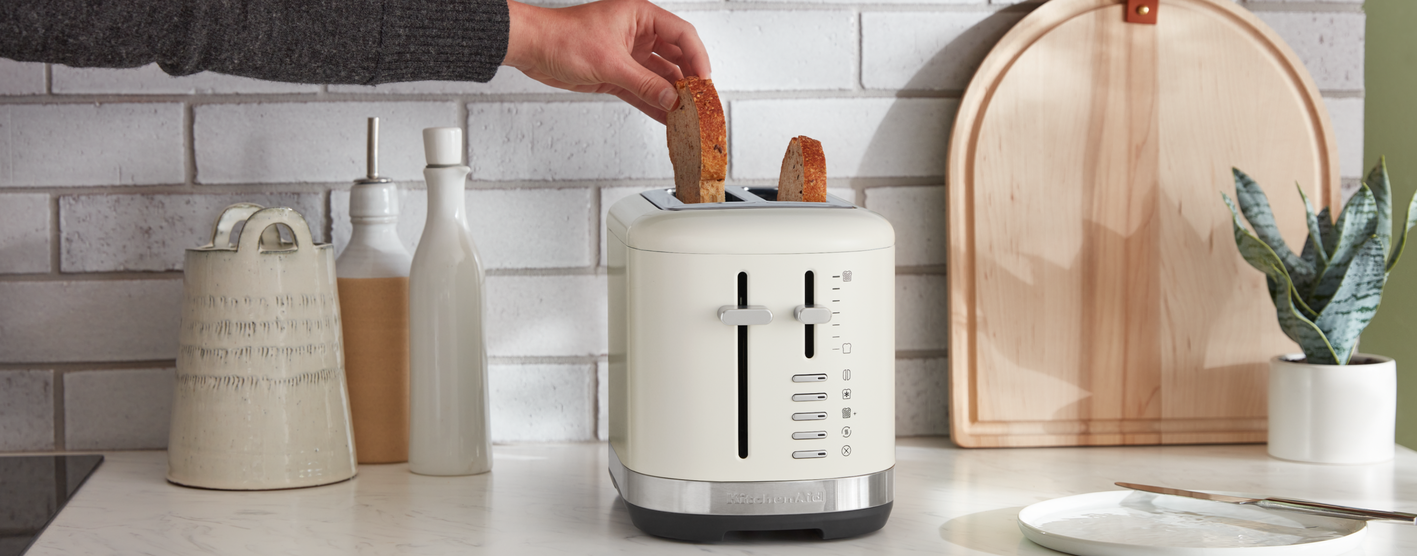 A person pulling a slice of toaster out of a KitchenAid® toaster.