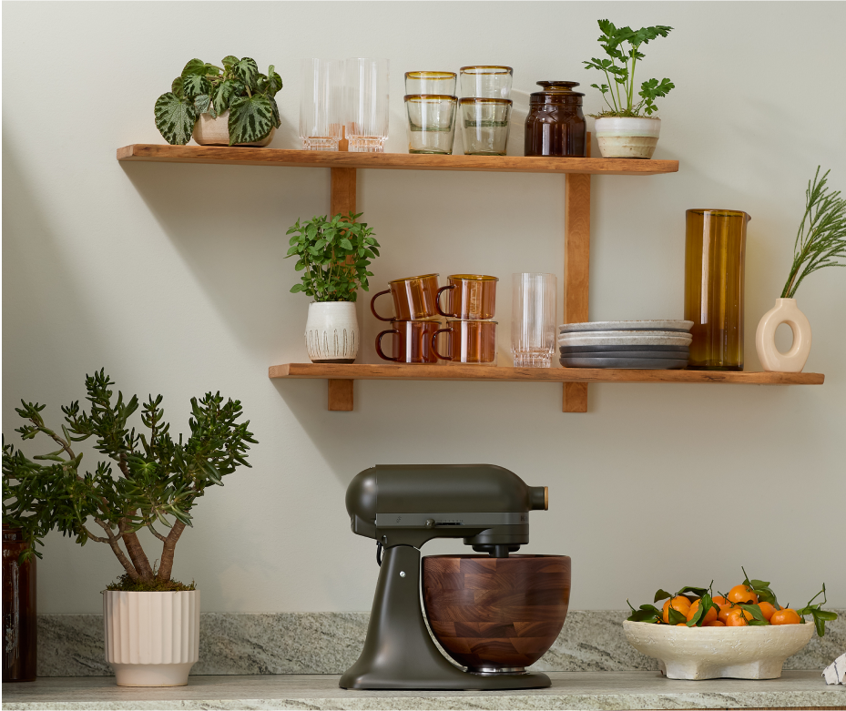 The Evergreen stand mixer on a countertop surrounded by greenery.