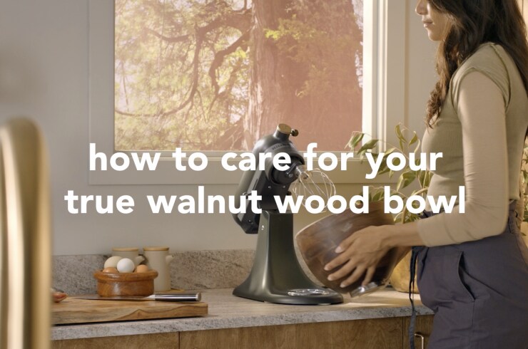 A person holding the true walnut bowl of the Evergreen stand mixer