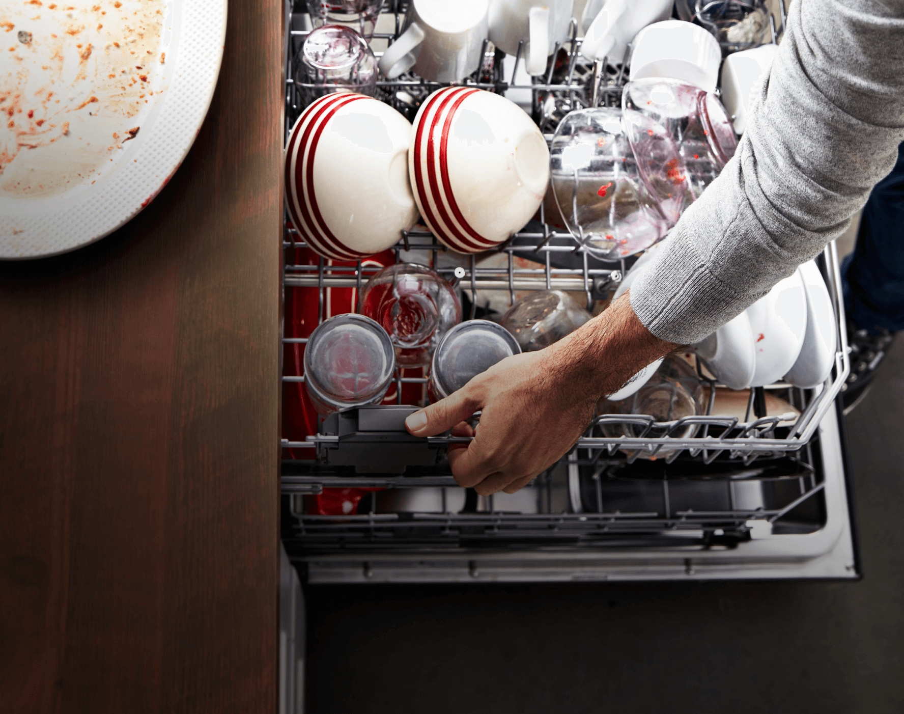 On the left, an open dishwasher viewed from above — packed with the aftermath of good cooking and a great meal.