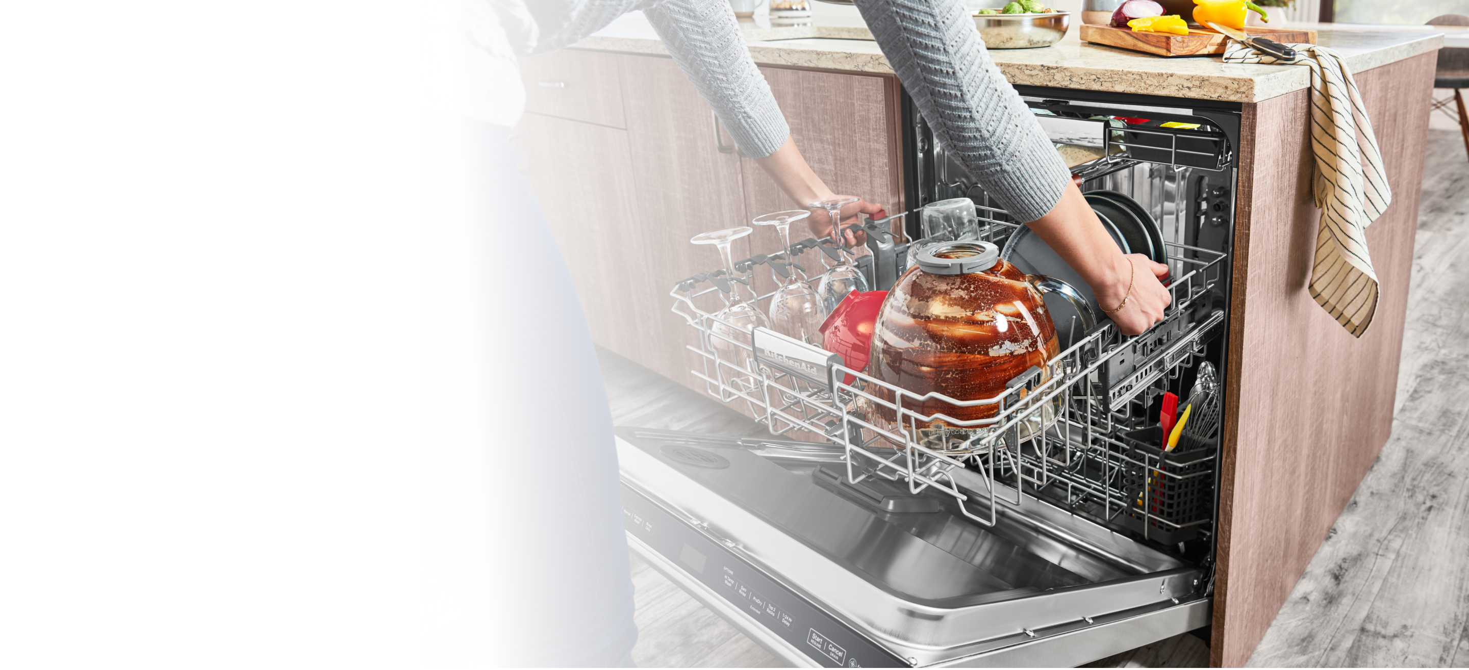 A person adjusting the middle rack of a KitchenAid® dishwasher.