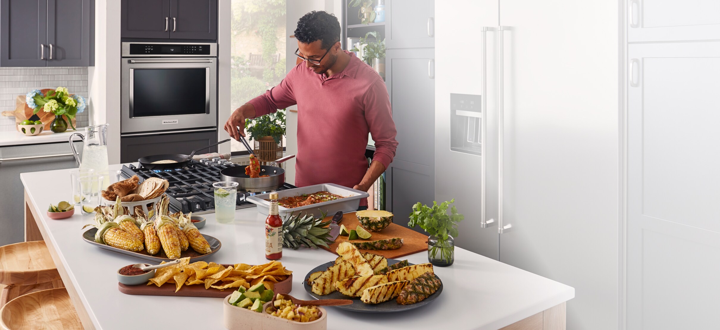 A person preparing barbecue and tapas in a bright kitchen