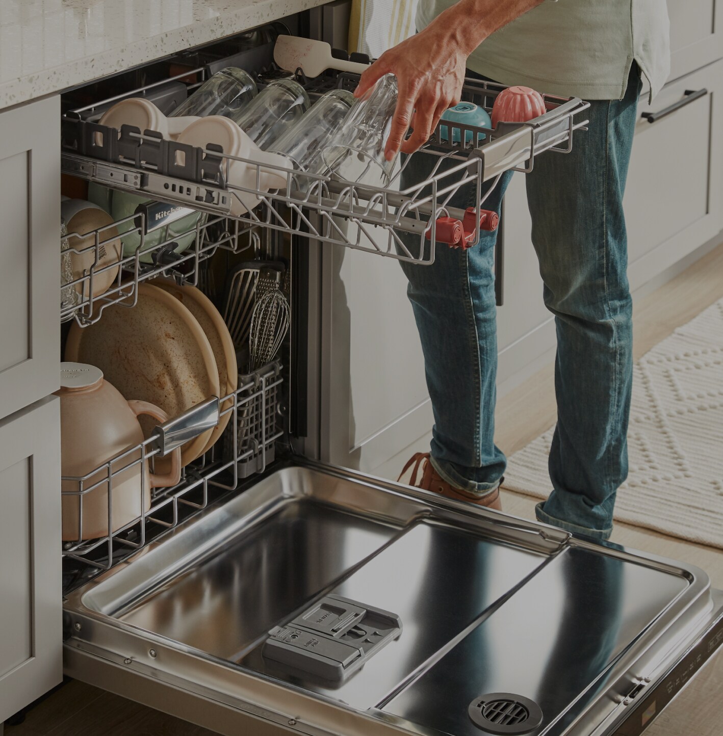A person loading dishes into a KitchenAid® dishwasher.