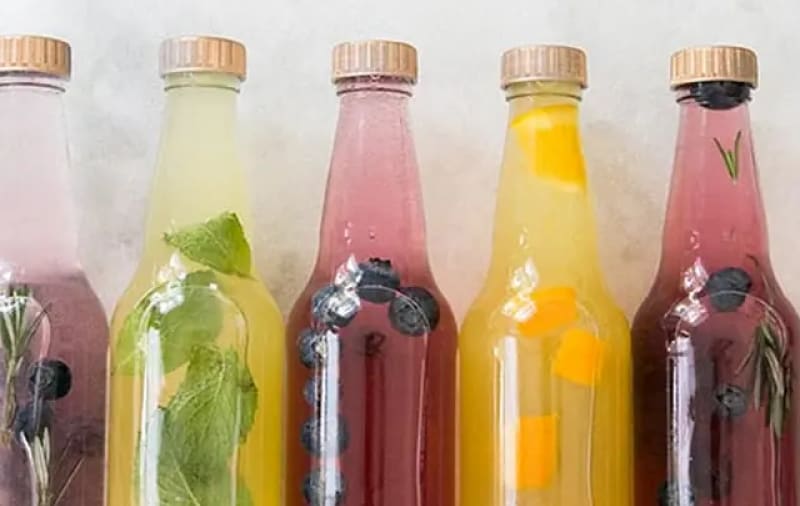 A row of bottles with fruit infused in liquid.