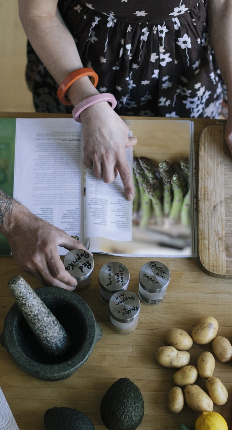 A woman reviewing an asparagus recipe with all of the required ingredients spread out on her table.