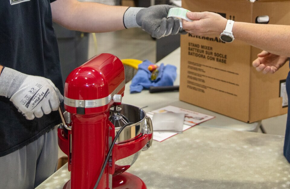 Technician testing a refurbished KitchenAid® mixer at the factory.