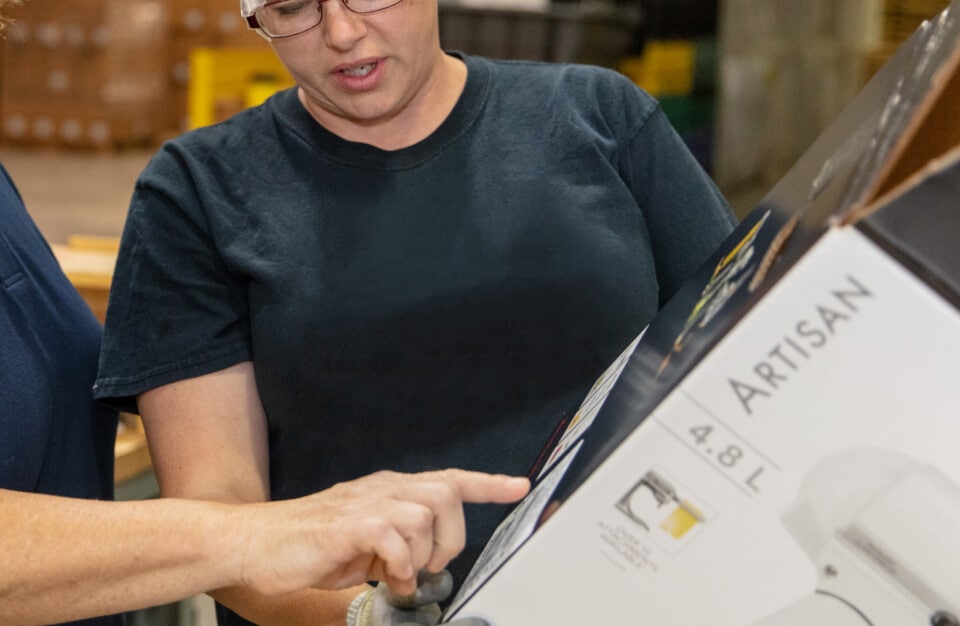 KitchenAid® technicians checking a refurbished appliance in new packaging.