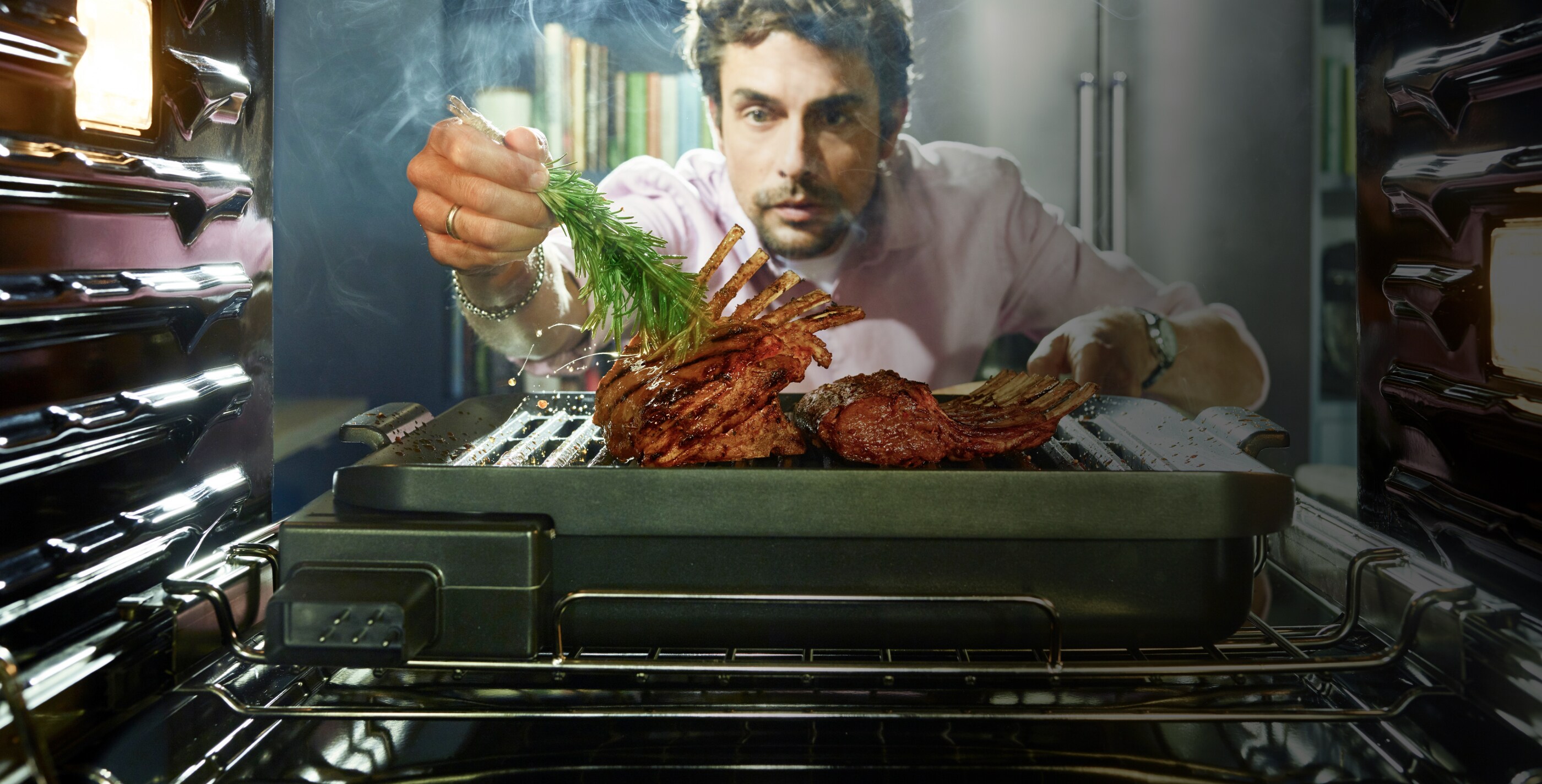 Man brushing a delectable roast with fresh rosemary, just coming out of the oven.