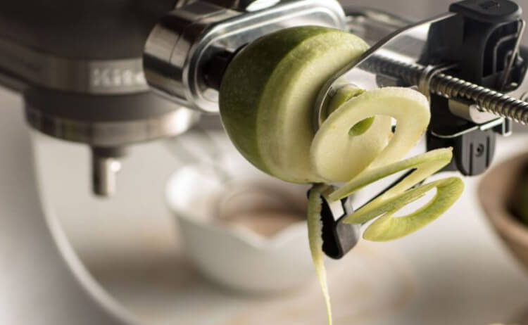A Spiralizer Attachment spiralizing a green apple.