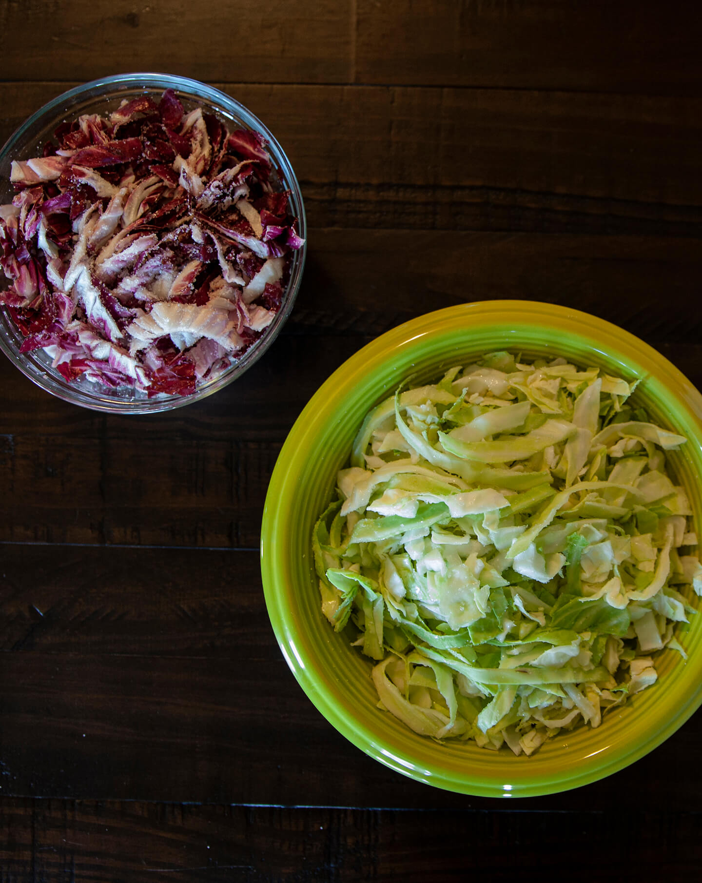 Chopped red and green cabbage resting in separate bowls.