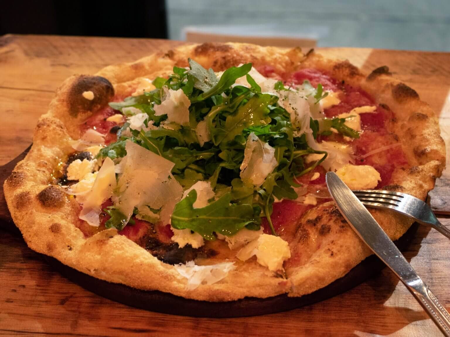 A fresh from the oven pizza presented on a wooden cutting board.