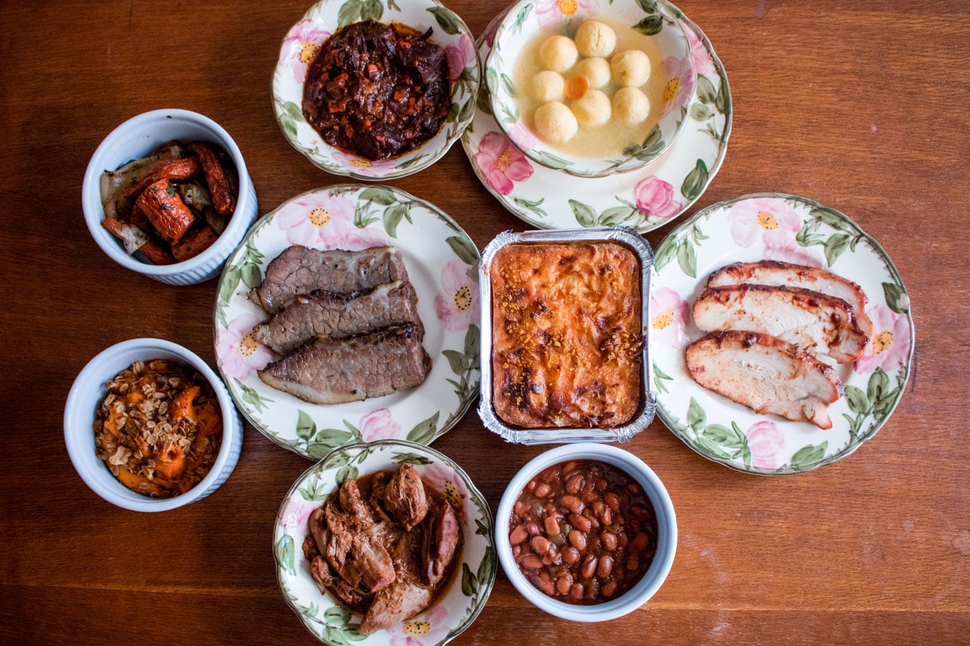 A table filled with decadent Jewish eats in served in floral china.
