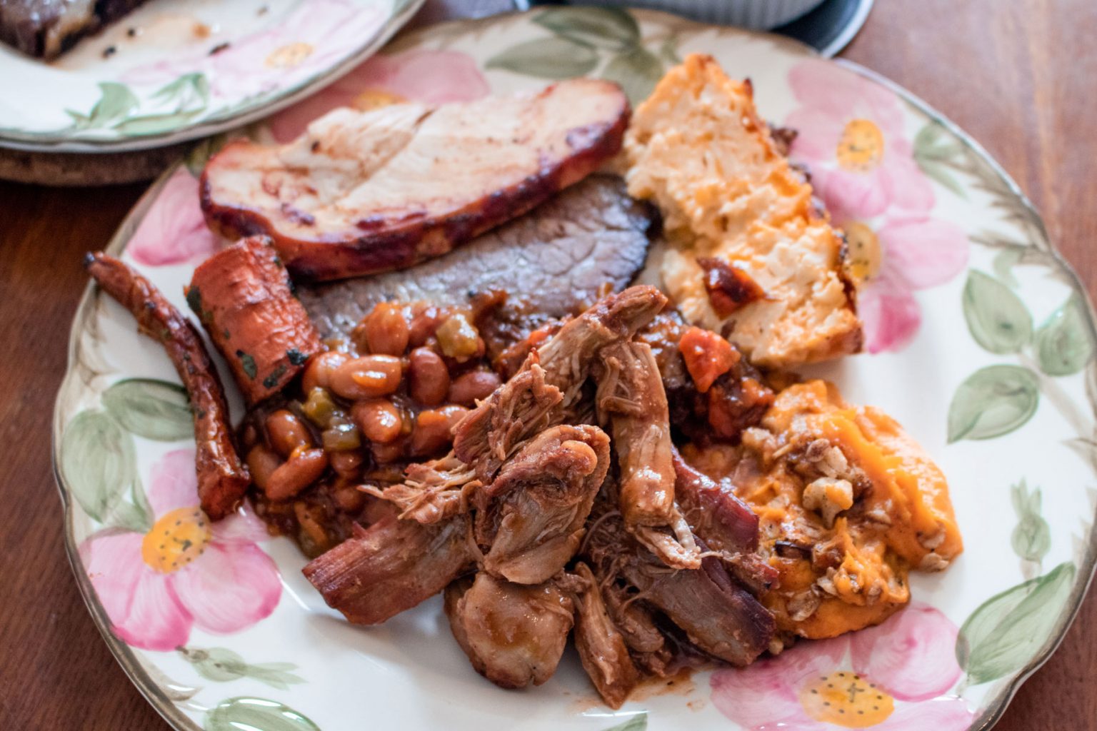 A floral plate filled to the brim with brisket, beans and more.
