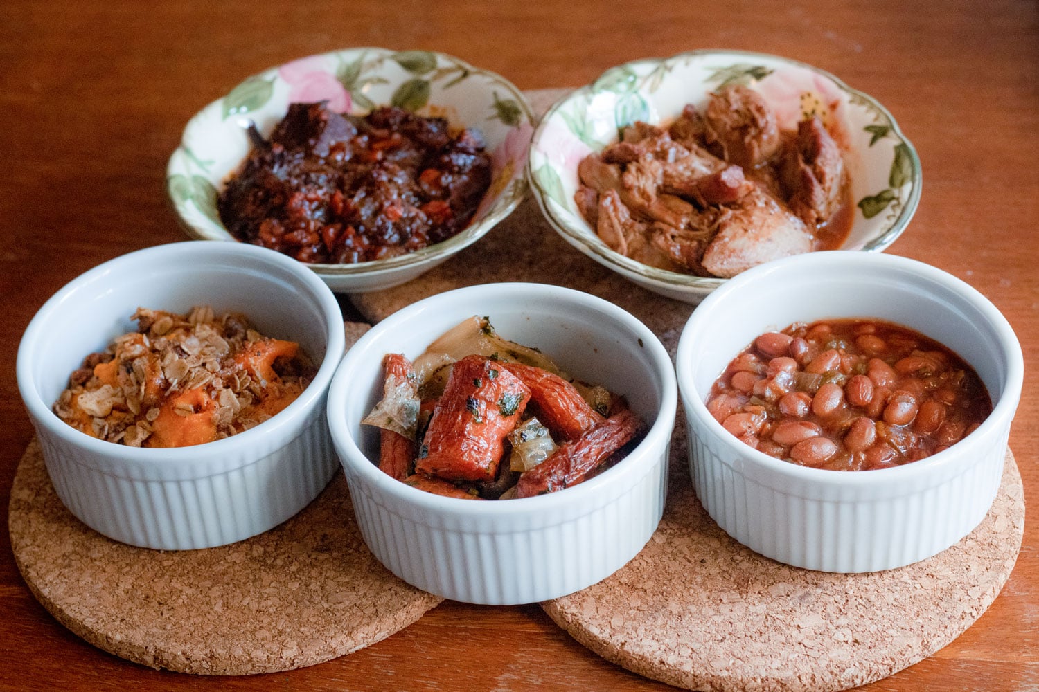 Small porcelain dishes of brisket, tzimmes and other delicious eats.