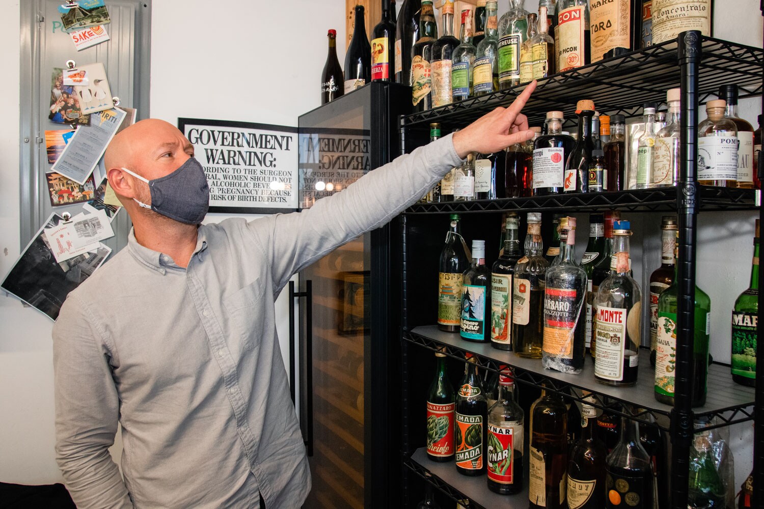 Aaron Sing Fox pointing out liquor bottles of Forthave Spirits.