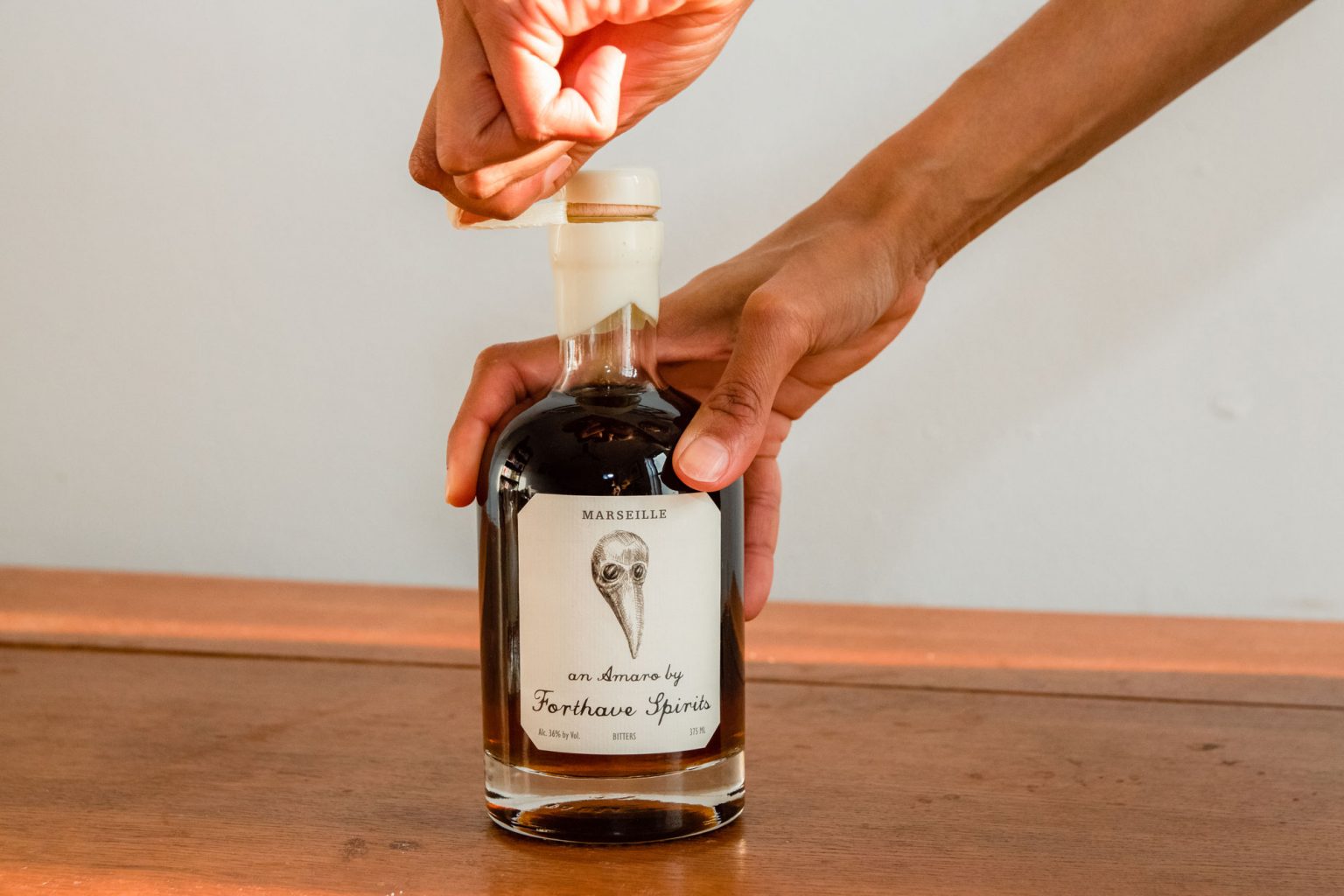 A person unwrapping the cork of a Forthave Spirit bottle.