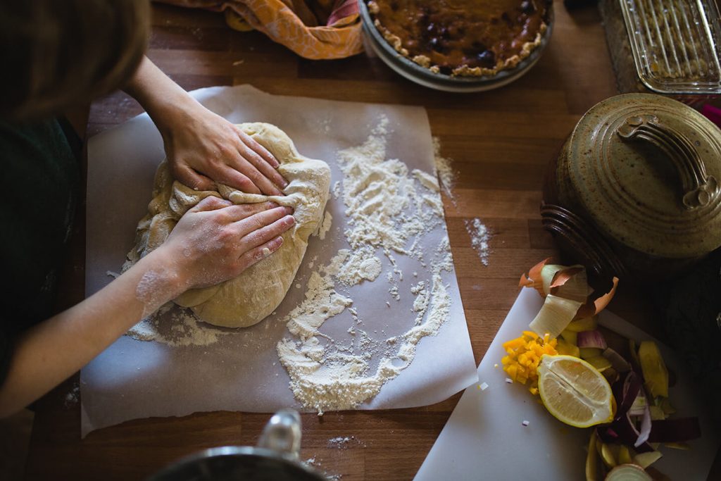 A person gently working dough with flour on parchment paper.