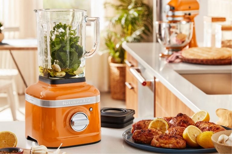 A honey blender filled with bright green ingredients.