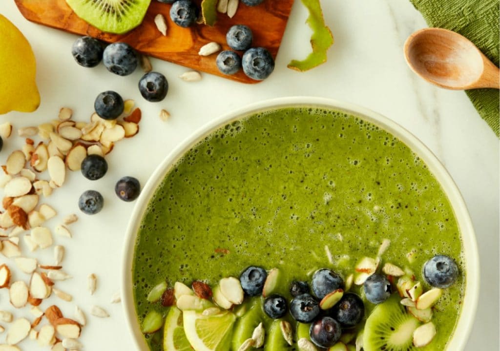 A bright green smoothie bowl with various ingredients.