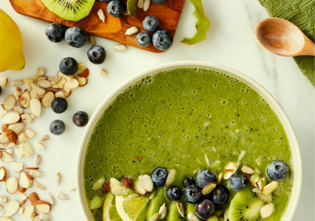 A bright green smoothie bowl with various ingredients.