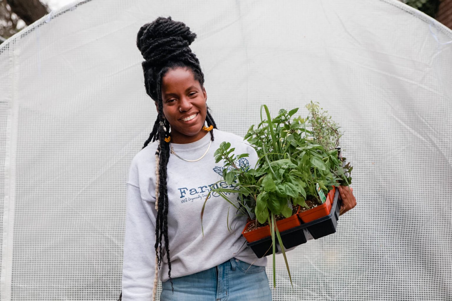 Christa holding a tray of plants as she smiles for a photo.