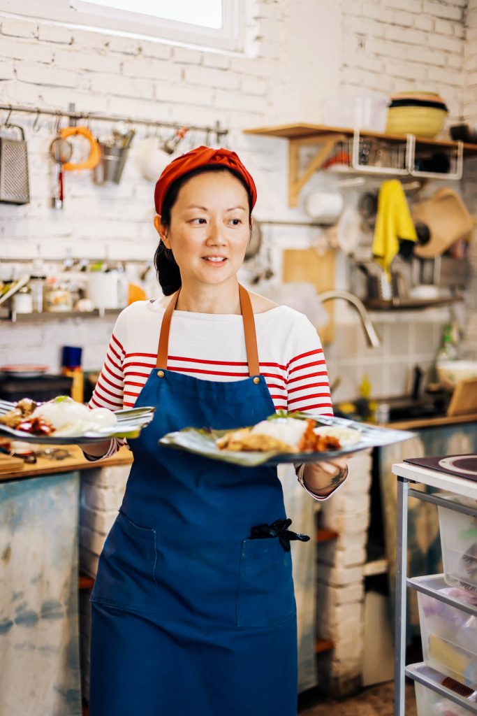 Limay Loo holding two large dishes. A large bowl of laska.