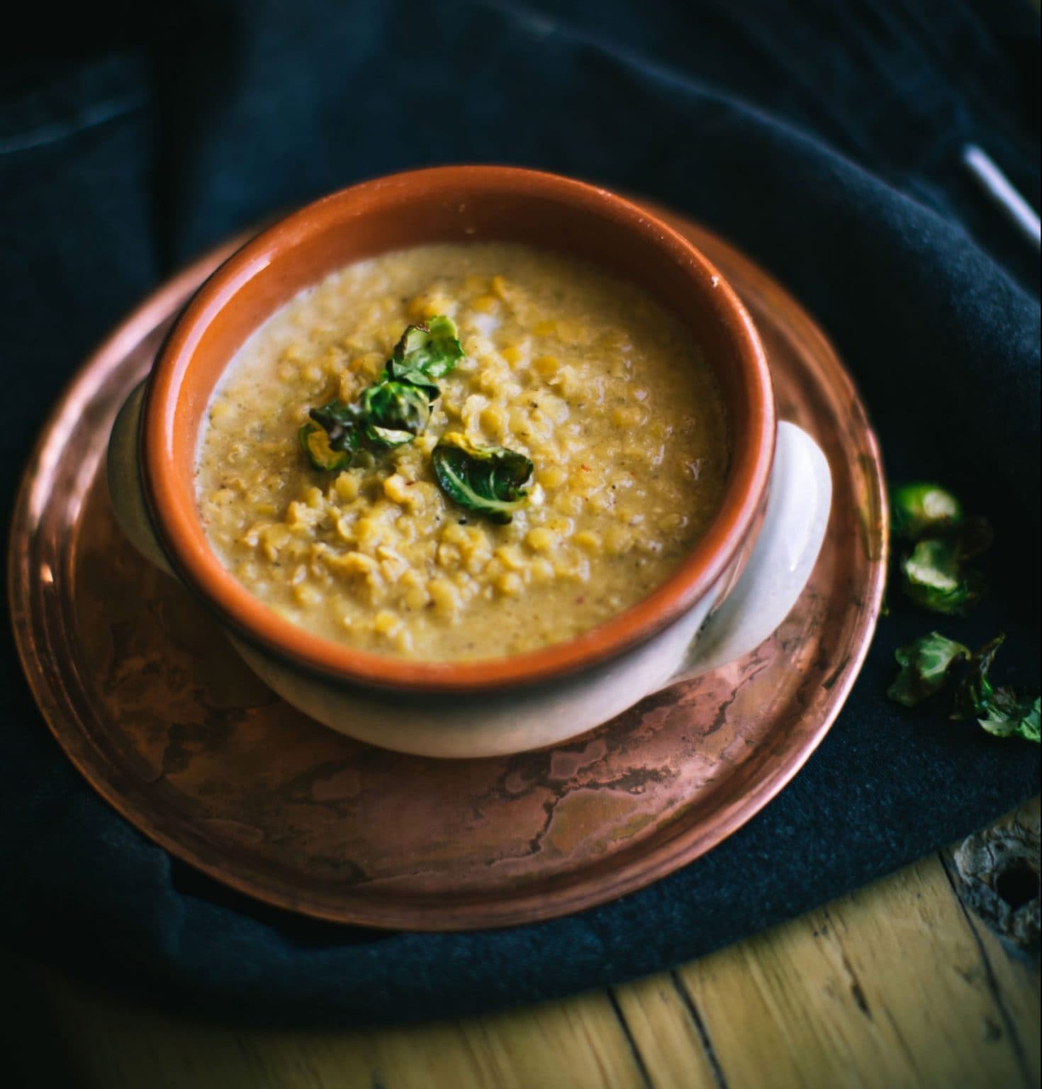 A light lentil soup in a bowl resting on an intricate plate.