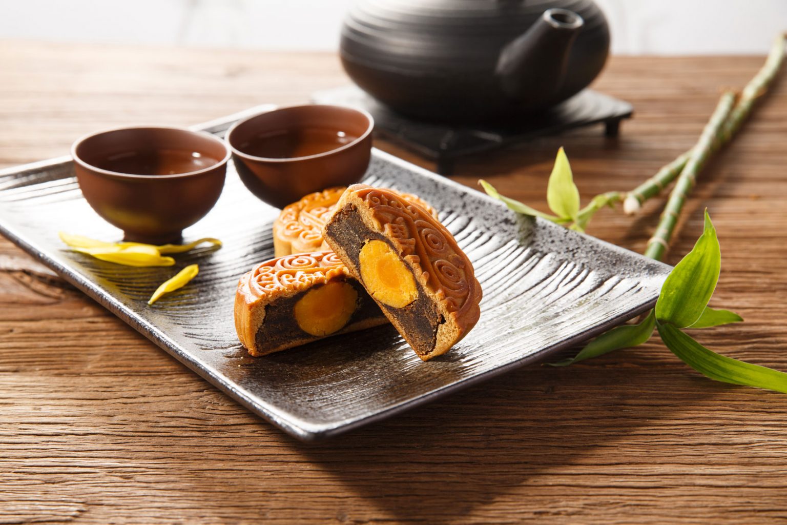 A set of mooncakes resting on a dark, rectangular plate.