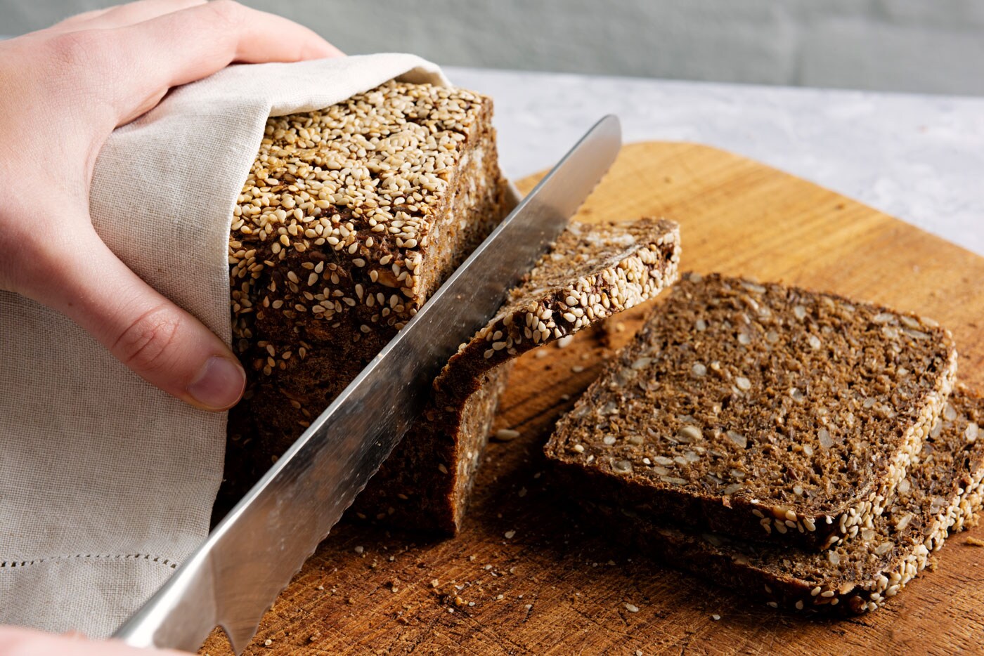 A person slicing rye bread.