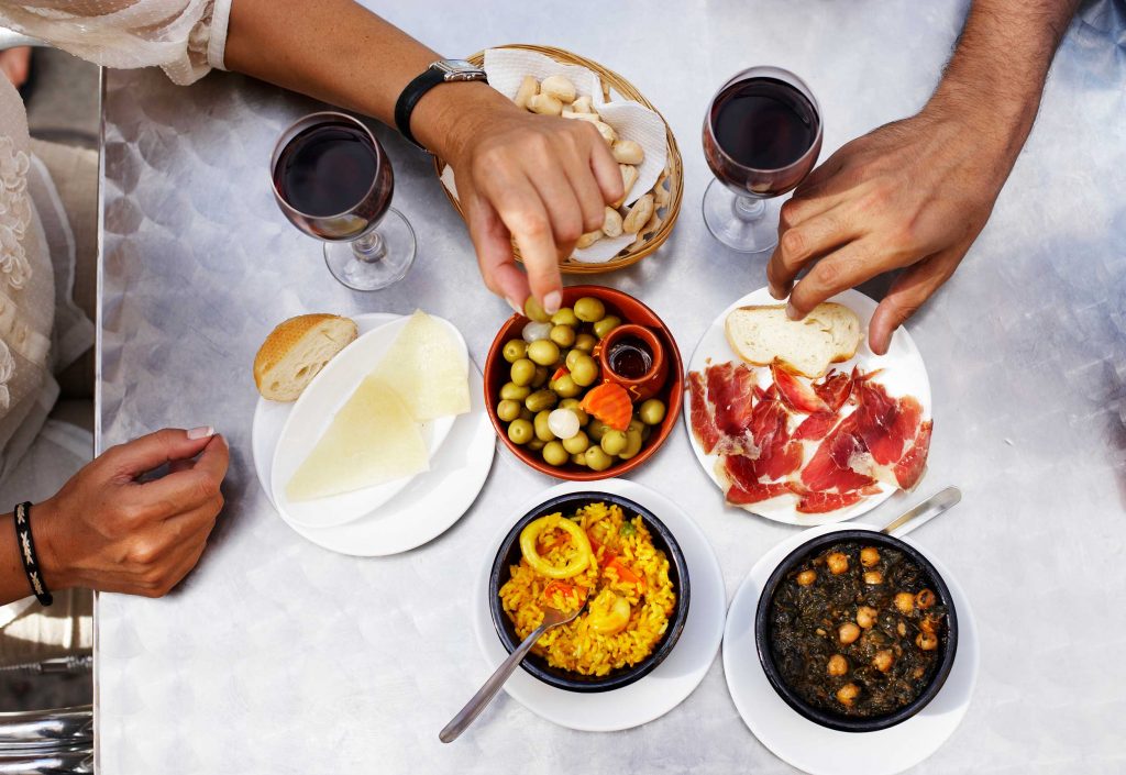 Friends gathered around a table filled with glasses of red wine and fine eats.