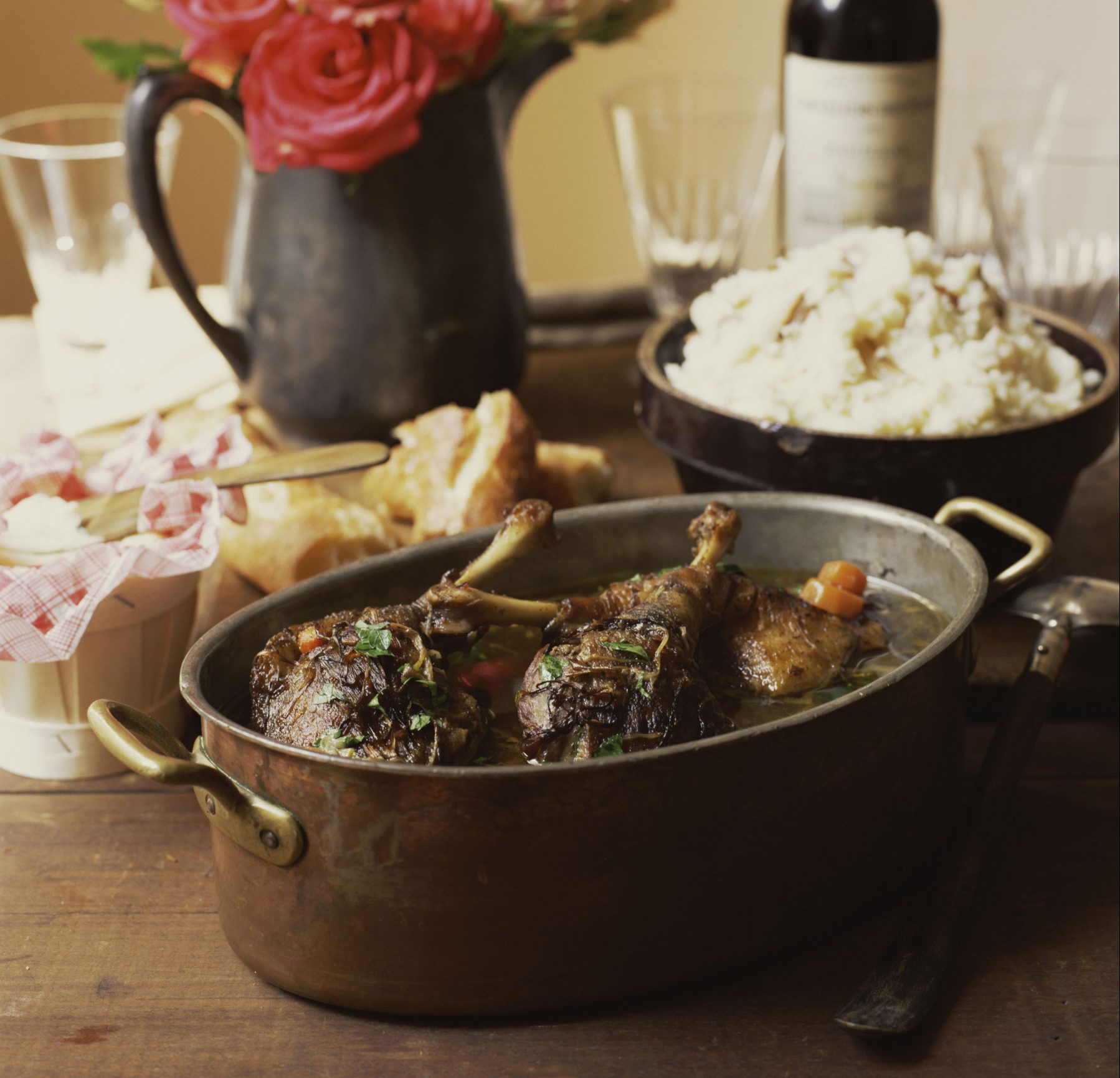 Roasted duck resting in a large pot resting on a wooden table.
