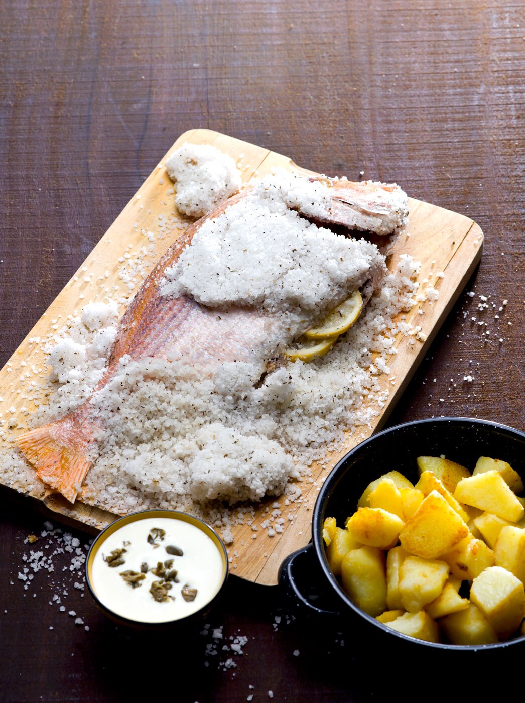 A whole fish in the process of being salt-crusted.