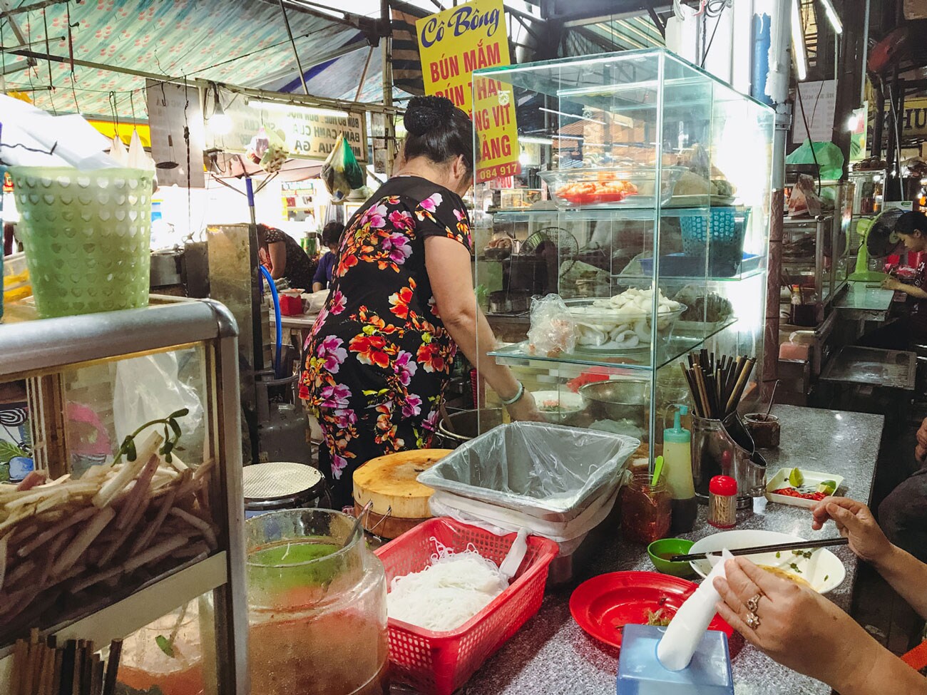 A person sitting at the counter of a busy food stall.
