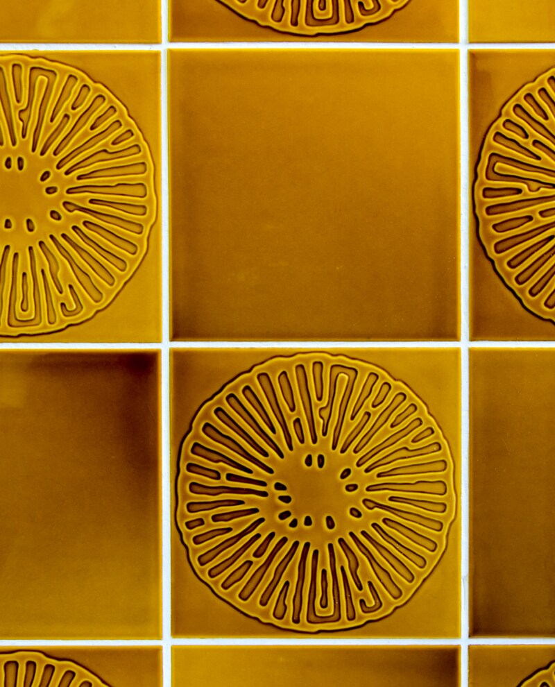 Tile with a warm color scheme and floral etched design