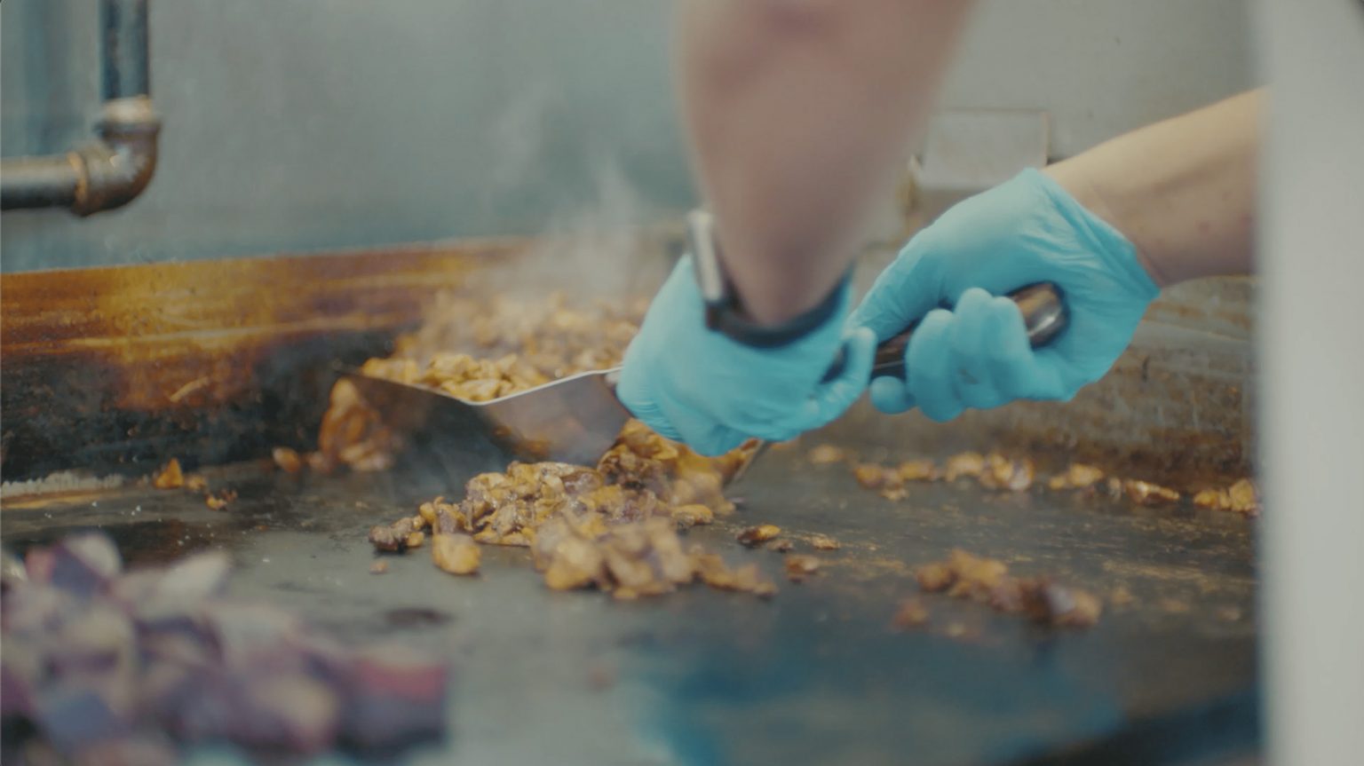 A person cooking over a flat top grill.