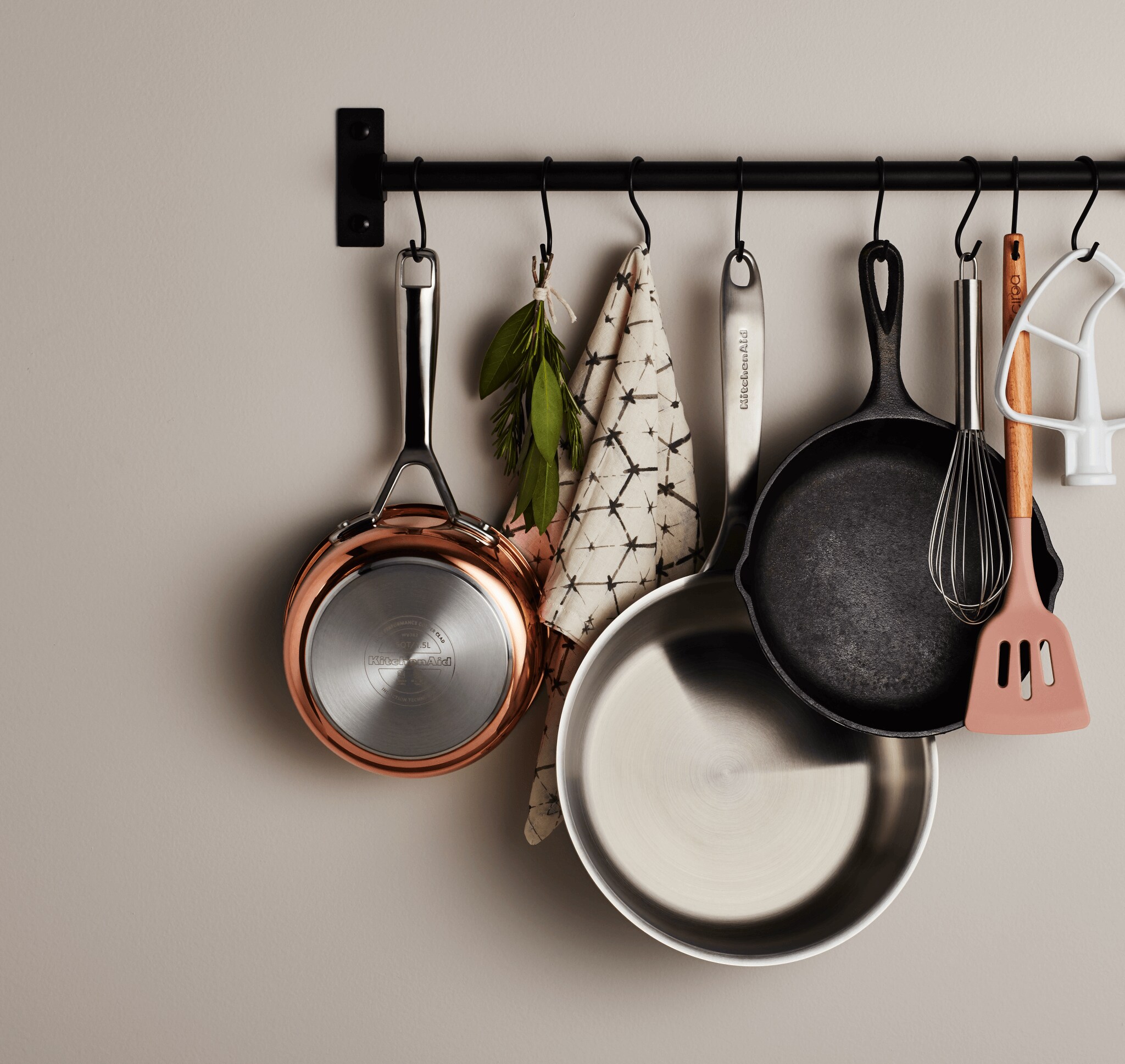 A collection of assorted pans and cookware hanging from a wall-mounted pot rack.