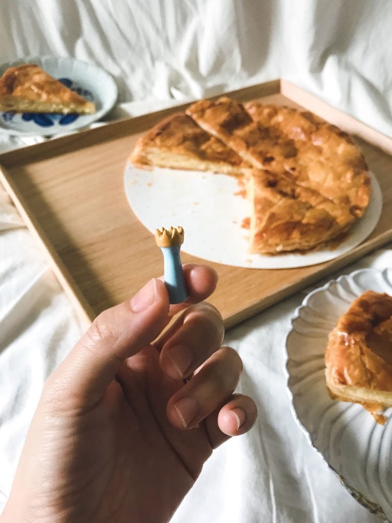 A person holding a porcelain fève from the galette des rois.