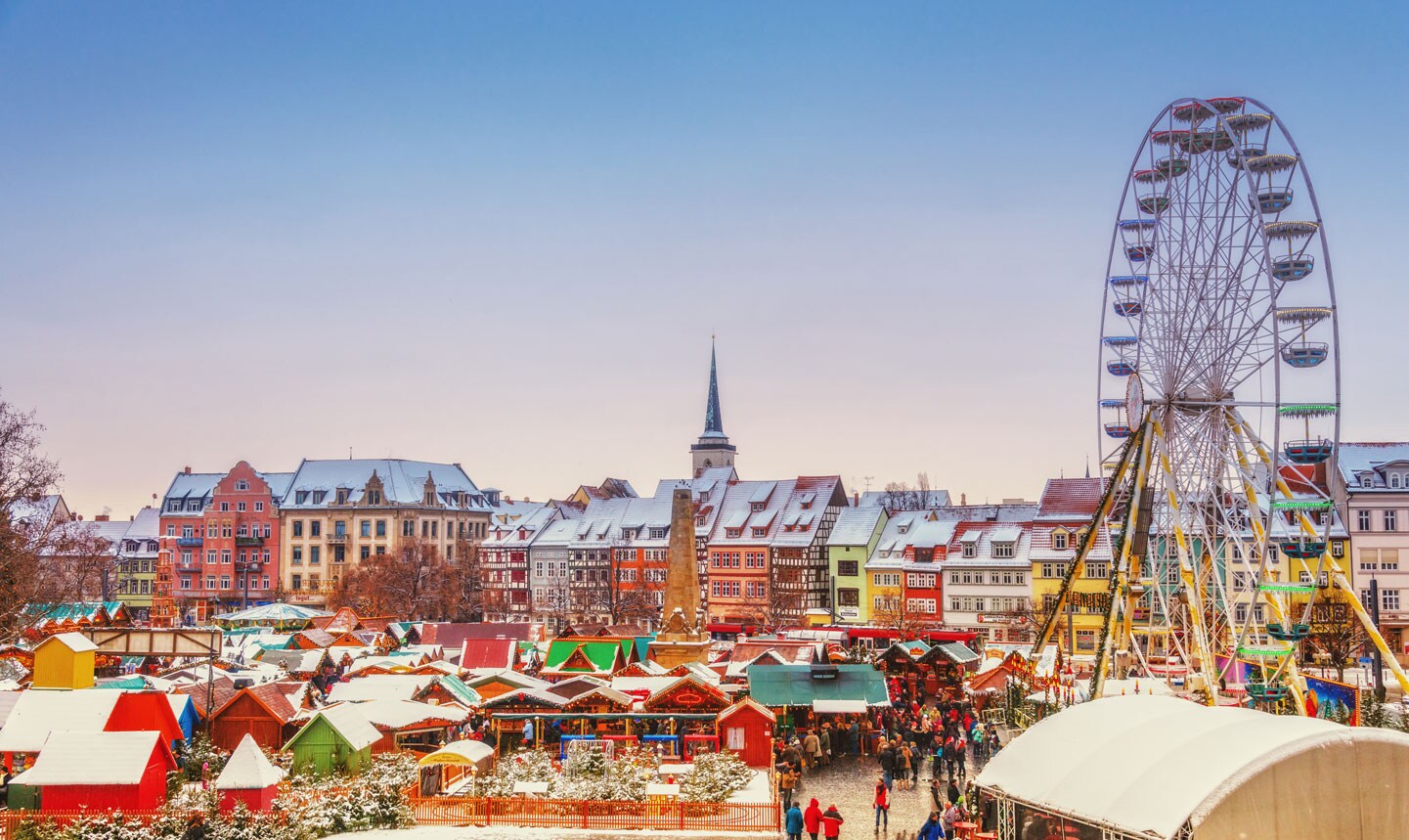A crowded Christmas market with a ferris wheel.