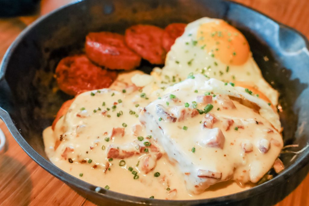 A dark bowl filled with biscuits and gravy.